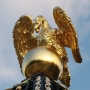 Zwieńczenie pawilonu stanowi posadowiona na kuli rzeźba zlatującego orła symbolizująca Zeusa Gromowładnego. W jego dziobie widzimy jabłko, które jako symbol władzy ofiarowane było Heraklesowi.