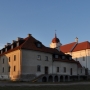 Widok na budynek dawnego klasztoru dominikanów. Za nim oświetlone zachodzącym słońcem ściany kościoła.